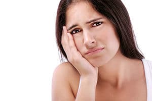 Woman holding jaw in pain.