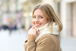Woman smiling with scarf and coat.