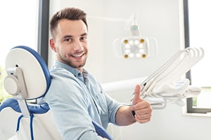 Man in dental chair giving thumbs up.