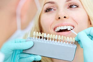 Woman smiling in dental chair with color matching for teeth.