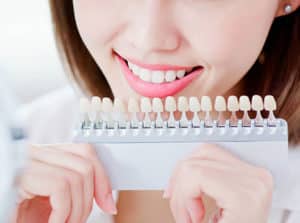 Woman holding teeth whitening scale while smiling.