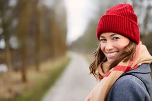 Woman smiling with red hat ad scarf walking away from camera.