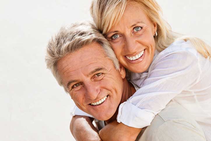 Older couple smiling man with wife on his back.