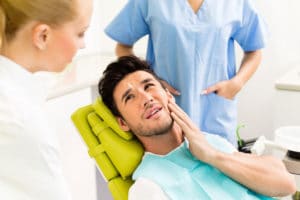 Man holding jaw in dental chair.