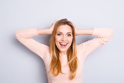Woman with Hands on Head Because She's Excited About The Best Cosmetic Dentist near Rochester MI