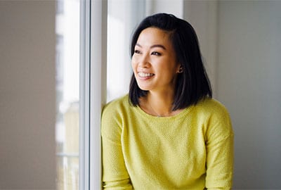 Woman Smiling Looking Out Window With Invisalign Clear Braces in Birmingham MI