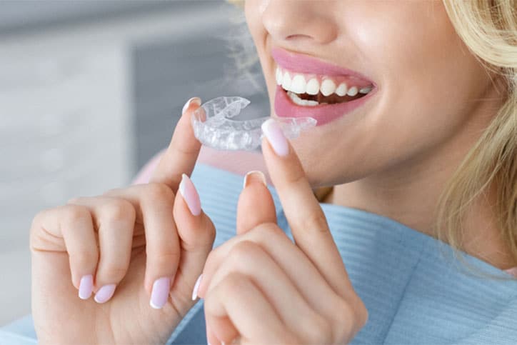 Woman Holding Invisalign Braces while Smiling