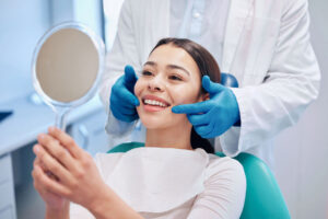Woman smiling in dental chair holding mirror