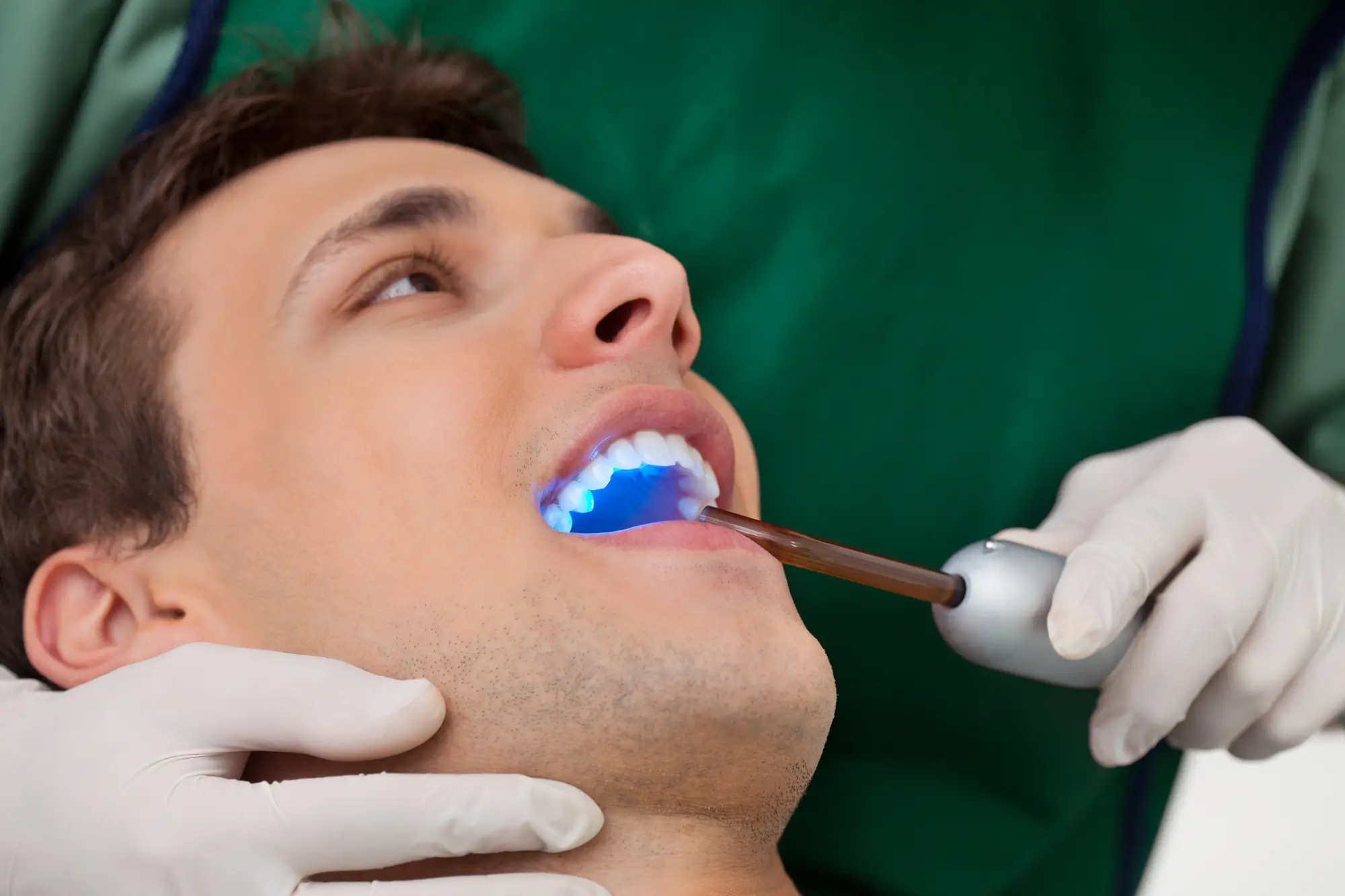 Dentist using UV light for Restorative Dentistry Birmingham MI procedure.