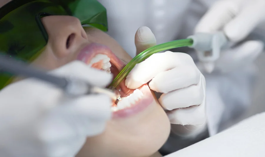 Dentist uses a suction tool during dentures treatment in Birmingham MI